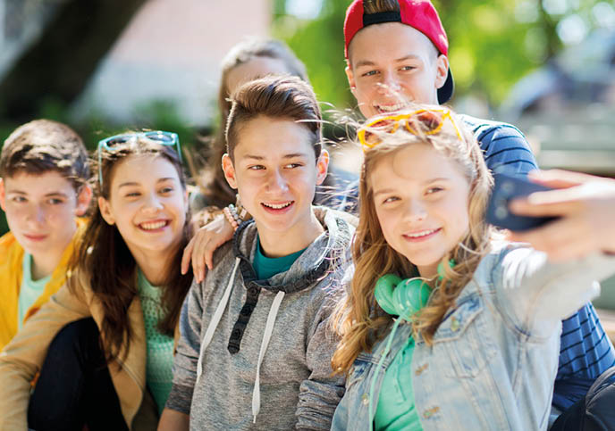 education, high school, technology and people concept - group of happy teenage students or friends taking selfie by smartphone