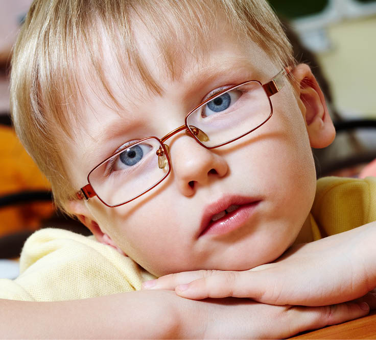 Close-up of schoolboy putting his head on arms and looking at camera