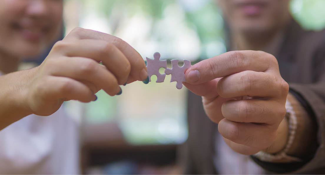 Man and woman hands holding and connecting two different jigsaw puzzle pieces